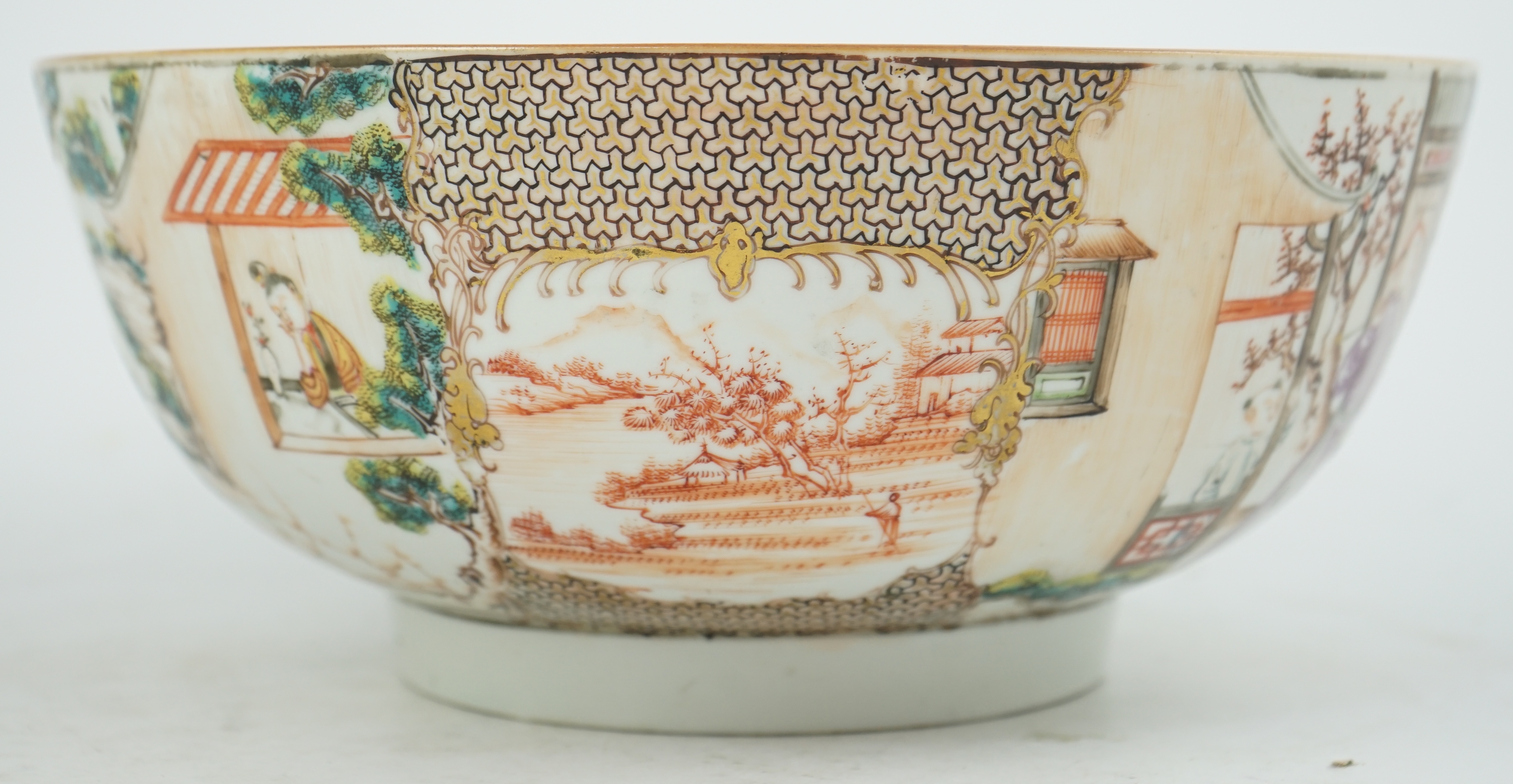 A Chinese famille rose ‘mandarin’ bowl, Qianlong period, painted with figures in a lakeside garden, between red enamelled landscape vignettes and cellular panels, 28.4cm diameter. Condition - there is a hairline crack to